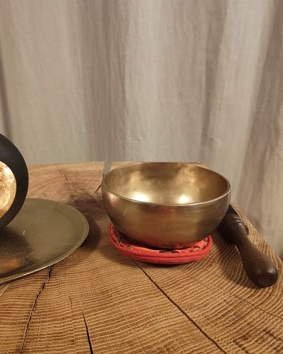 Klangschale mit hölzernem Klöppel auf einer Holzplatte